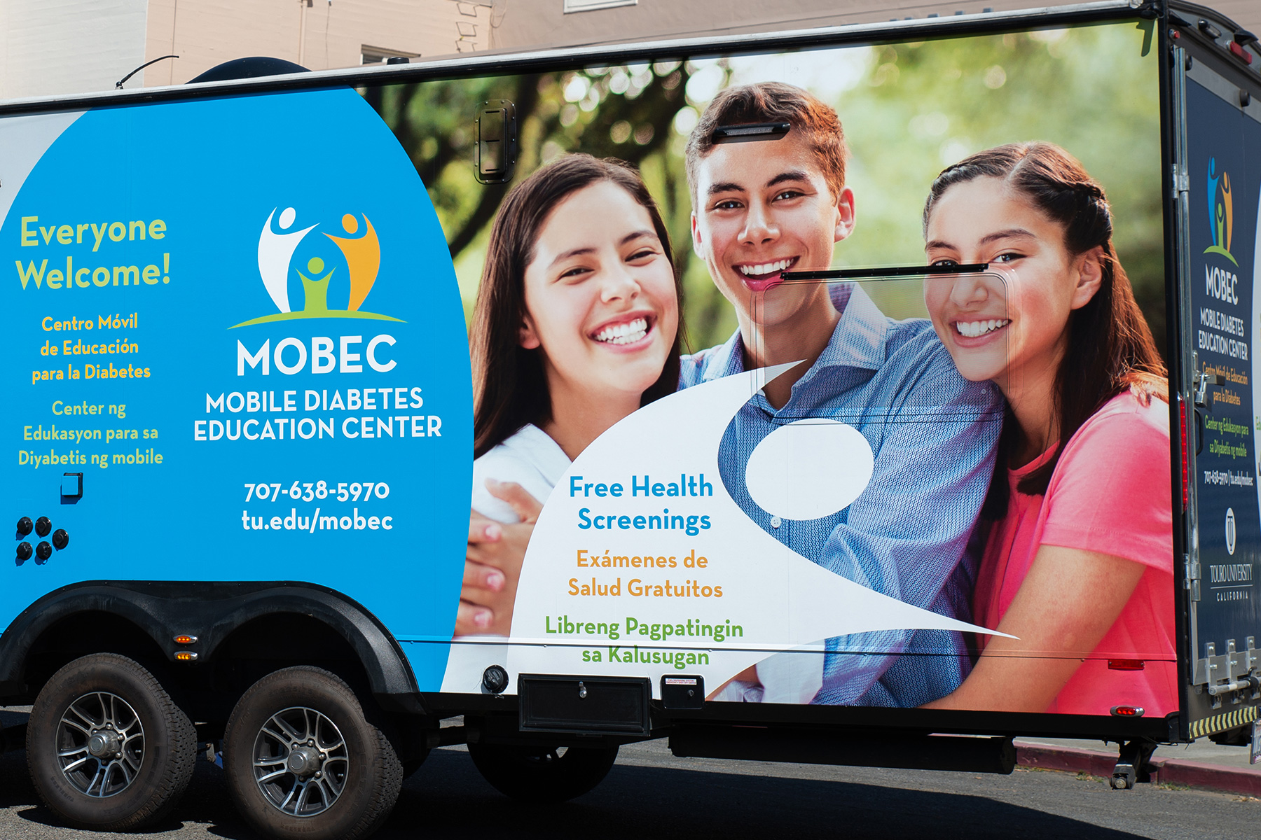 bus with mobec logo and images of two women and a man, and a man woman and child
