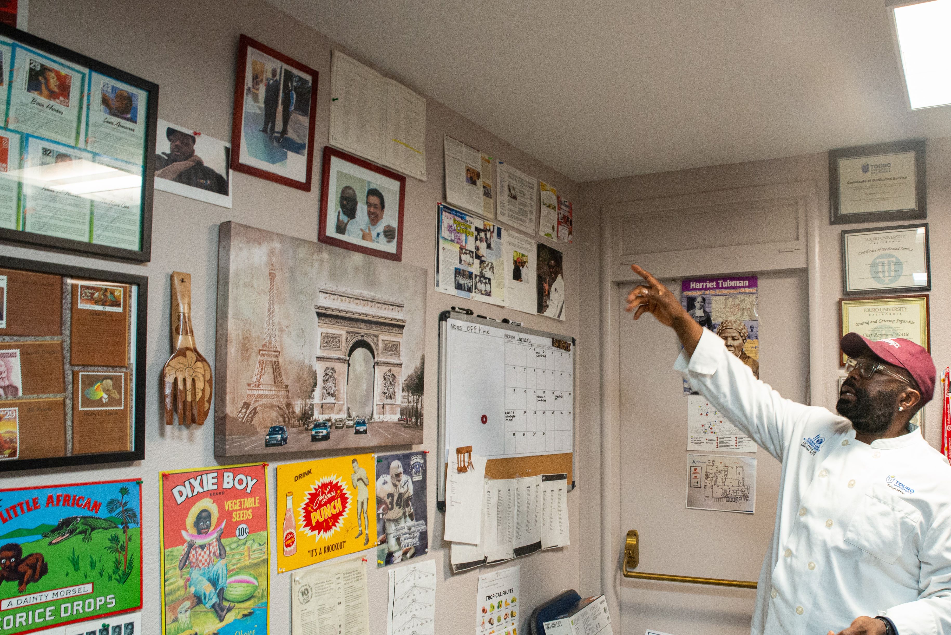 Chef Raymond Nottie points to a wall covered with items from African American history