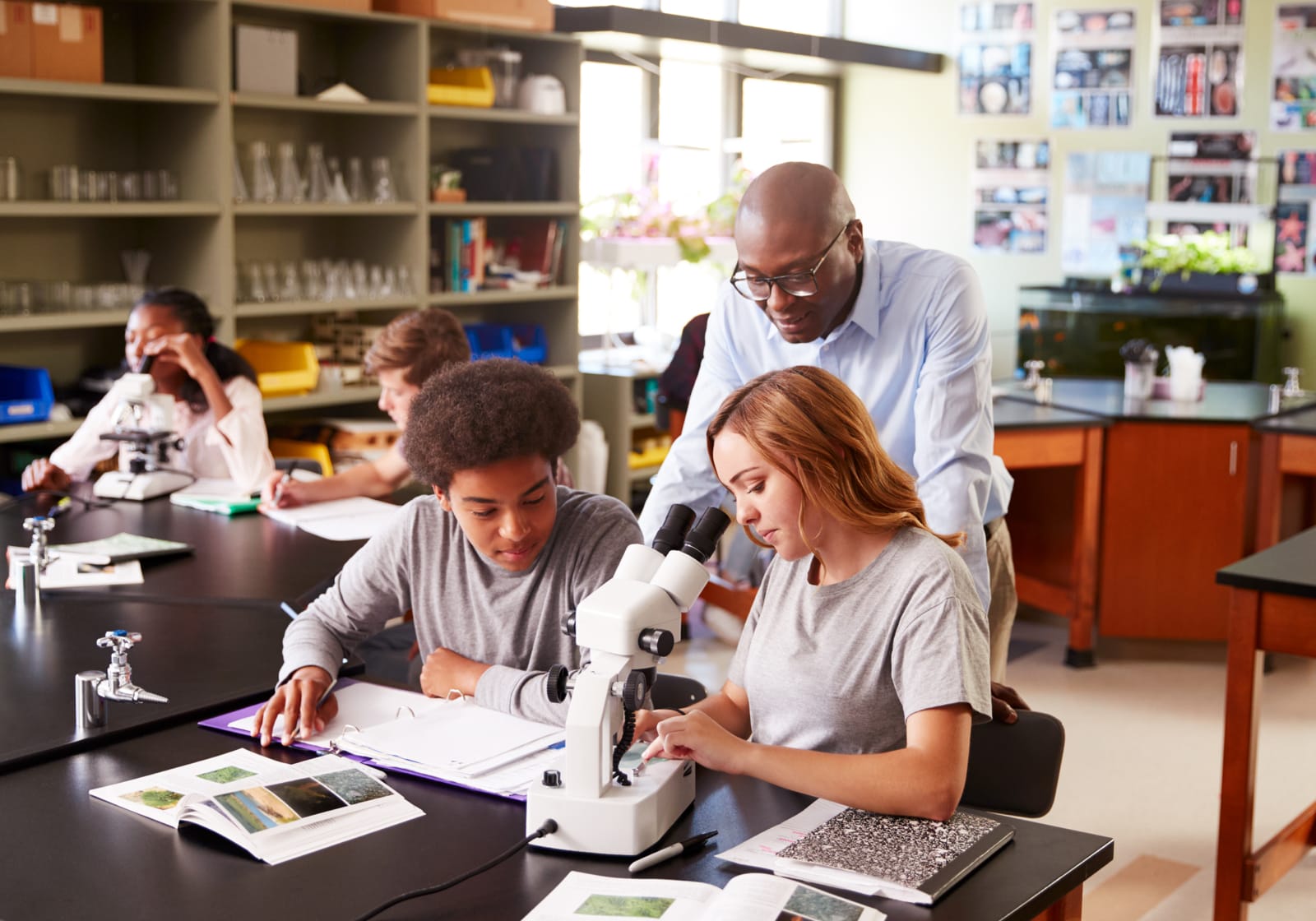 teacher with high school students looking through microscope