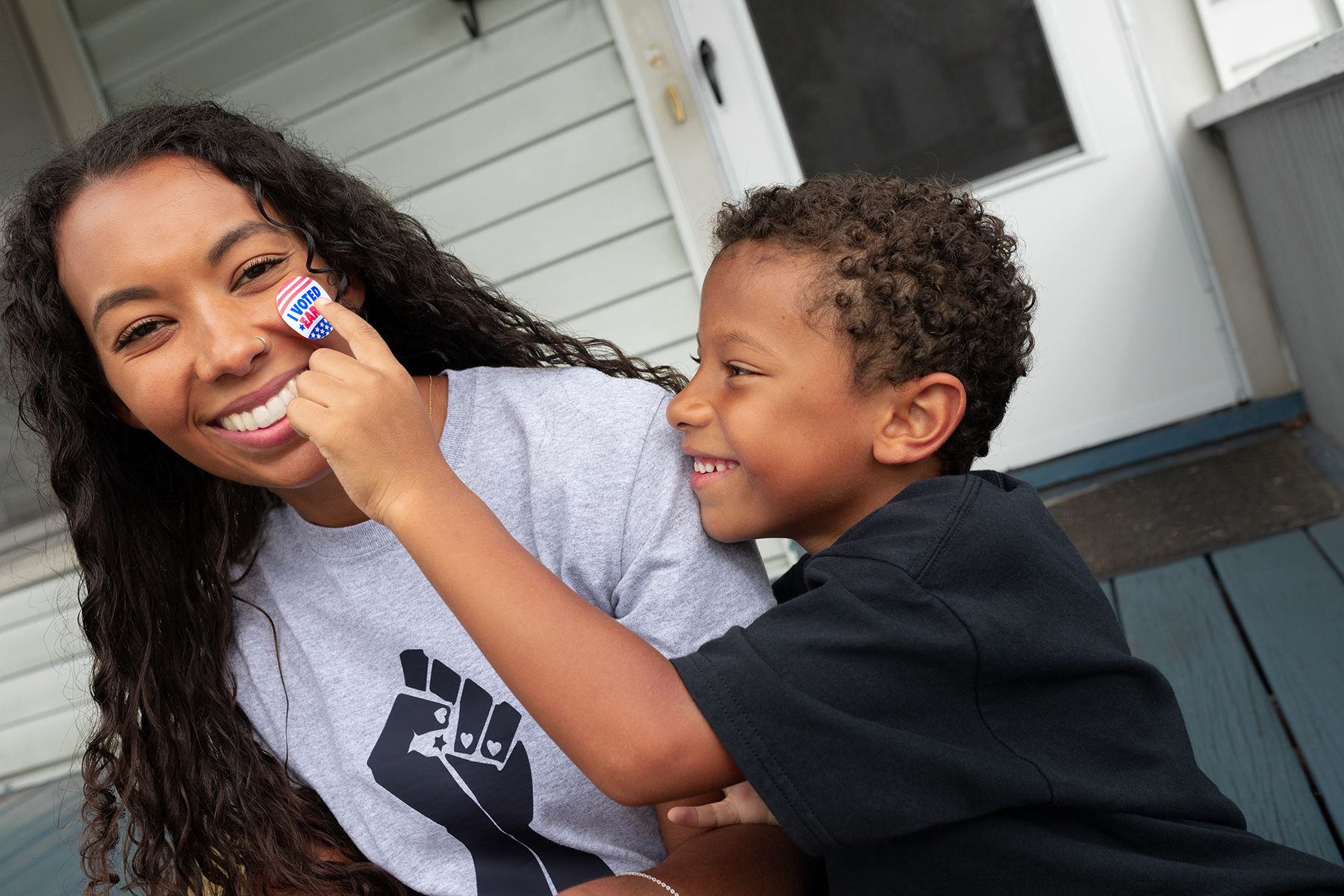 Smiling young boy placing a sticker on a smiling woman\'s cheek