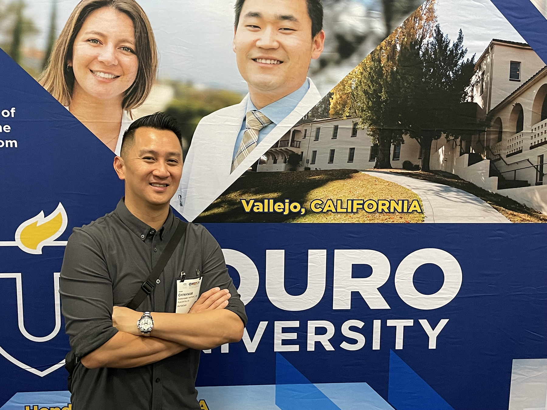 A photo shows Dr. Chinhnam Hathuc (DO Class of 2010) at the Touro University Colleges of Osteopathic Medicine booth in the Exhibit Hall of the Henry B. González Convention Center in San Antonio during the American Osteopathic Association\'s Osteopathic Medical Education Conference, or OMED, Sept. 20, 2024.