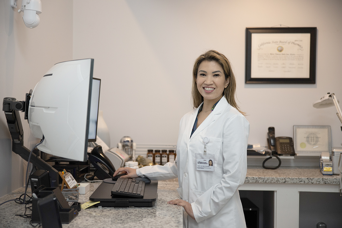 A photo shows Dr. Rizza Alcaria, the Pharmacy Manager at Central Pharmacy in Vallejo, as she stands inside a patient meeting area within the pharmacy.